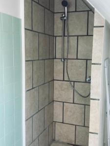 y baño con ducha y pared de azulejos. en Vejlegades skomager, en Nakskov