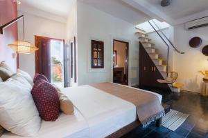 Un dormitorio con una gran cama blanca y una escalera en Rambutan Resort – Siem Reap, en Siem Reap