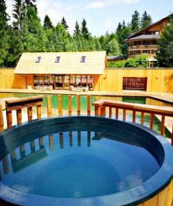 una bañera de hidromasaje en una terraza con una casa al fondo en Ribno Luxury Glamping, en Bled