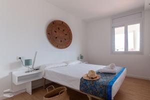 a white bedroom with a bed with a hat on it at Vista Roses Mar - Apartamento con piscina II in Roses