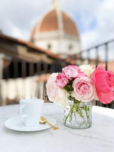Duomo Suites Florence في فلورنسا: مزهرية من الورد الزهري وكوب من القهوة