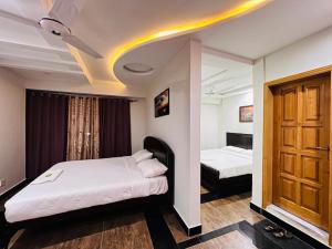 a bedroom with two beds and a wooden door at AAKAS Hotel & Restaurant in Muzaffarabad