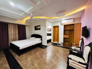 a bedroom with a bed and a tv and a couch at AAKAS Hotel & Restaurant in Muzaffarabad