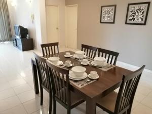 een eetkamer met een tafel en stoelen en een televisie bij Noble Villa Apartment in George Town