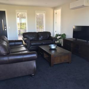 a living room with a leather couch and a coffee table at Dunray Cottage - Welcome to Havelock North in Hastings