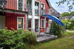 a table and chairs on a porch with an umbrella at Ferienwohnungen Haus am Deich in Prerow