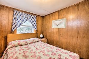 a bedroom with wood paneling and a bed and a window at No-Frills Hampton Cottage - Steps to Beach! in Hampton
