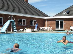 two people in a swimming pool with a slide at 6 person holiday home in Rømø-By Traum in Sønderby