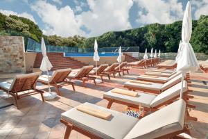 - une rangée de chaises longues et de parasols sur la terrasse dans l'établissement GRIFID Hotel Foresta - All Inclusive & Free Parking - Adults Only, aux Sables d'or