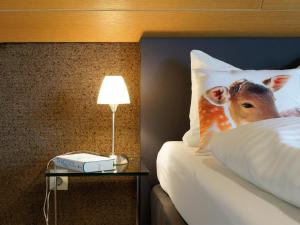 a bed with a pillow with a picture of a cow on it at Landpension Am Sommerhang in Bad Rippoldsau