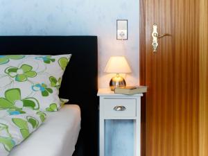 a bed with a nightstand with a lamp and a pillow at Landpension Am Sommerhang in Bad Rippoldsau