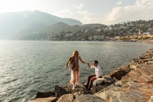 a man and a woman standing on rocks by the water at Hotel Eden Roc - The Leading Hotels of the World in Ascona
