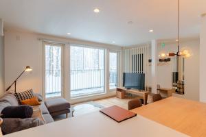 a living room with a table and a large window at ROKU by H2 Life in Niseko