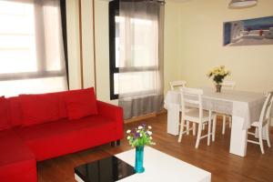 a living room with a red couch and a table at Apartamentos Rodriguez de Córdoba 3000 in Zaragoza