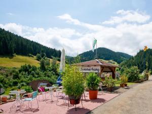 un restaurant avec des chaises, des tables et un drapeau sur une montagne dans l'établissement Landpension Am Sommerhang, à Bad Rippoldsau-Schapbach