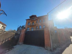 Homelike B&B في تبليسي: منزل خلف سياج وخلفه الشمس