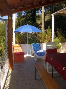 une terrasse avec un parasol bleu, des chaises et un banc dans l'établissement Apartment Dario, à Gruda