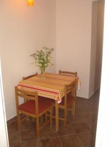 Apartment Dario في Gruda: طاولة غرفة الطعام مع إناء من الزهور عليها