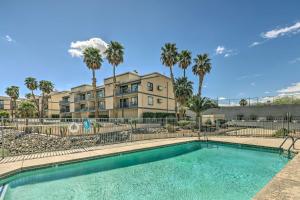 a swimming pool in front of a building with palm trees at Bullhead City Condo with Direct River Access! in Bullhead City