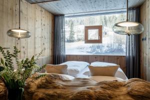 een slaapkamer met een groot raam en een bed met 2 stoelen bij mama thresl in Leogang