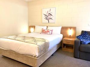 a bedroom with a large bed and a chair at Apollo Motel Parkes in Parkes