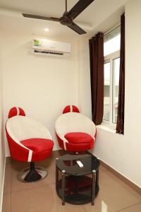2 chaises rouges et une table dans une pièce dans l'établissement Grace Apart Hotel @Kochi, à Cochin