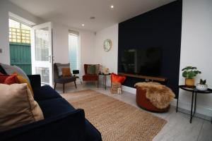 a living room with a blue couch and a tv at Bath Luxury City Centre 4 Bedroom Townhouse, Sleeps 8, Easy Parking, Private Courtyard Garden, by EMPOWER HOMES in Bath