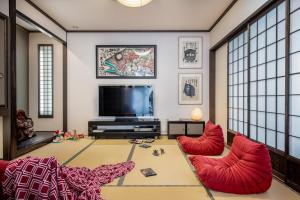 Il comprend un salon doté de fauteuils rouges et d'une télévision à écran plat. dans l'établissement Shochikubai by H2 Life, à Furano