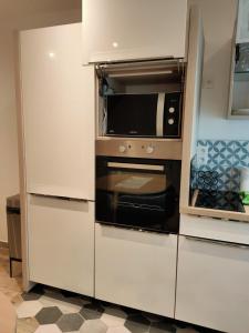 a white kitchen with a microwave and a stove at Le125 in Saultain
