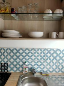 a kitchen counter with a sink and a shelf with dishes at Le125 in Saultain
