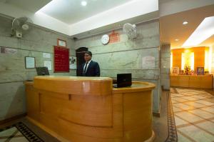 ein Mann steht hinter einer Bar in einem Restaurant in der Unterkunft Hotel Metropolitan in Neu-Delhi