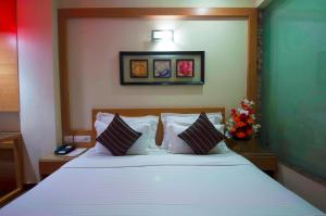 ein Schlafzimmer mit einem großen Bett mit weißen Laken und Kissen in der Unterkunft Hotel Metropolitan in Neu-Delhi