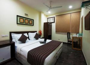 ein Hotelzimmer mit einem großen Bett und einem Schreibtisch in der Unterkunft Hotel Metropolitan in Neu-Delhi + 6 Fotos