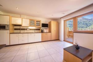 a kitchen with white cabinets and a large window at Fewo Sonnenaufgang - Zeppichl in Pfelders +15 photos