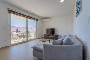 a living room with a couch and a television and a balcony at Blue Pearl Apartment in Cres
