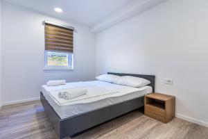 a white bedroom with a bed and a window at Blue Pearl Apartment in Cres