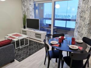 a living room with a table and chairs and a television at Aurinkoranta Apartments by Hiekka Booking in Kalajoki