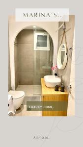 y baño con lavabo, aseo y espejo. en Marine's luxury home, en Votsi
