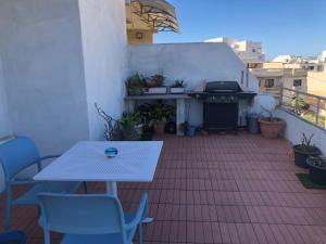 a patio with a grill and a table and chairs at Penthouse in Kappara in San Ġwann