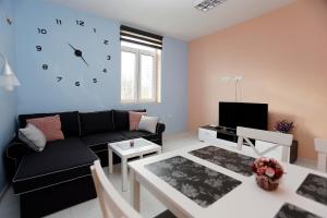 ein Wohnzimmer mit einem Sofa und einer Uhr an der Wand in der Unterkunft Lux Apartment " Central street " in Burgas City