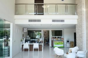 a living room with white chairs and a table at The September Salaya in Salaya