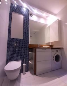 a bathroom with a toilet a sink and a washing machine at Apartament Rokosowska in Warsaw