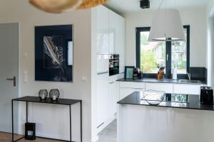a kitchen with white cabinets and a black counter top at Wellnesshaus "Strandflieder" mit Sauna, Kamin & Terrasse - ruhig & stilvoll in Zingst in Zingst +6 photos