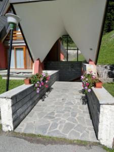 a building with two benches with flowers and a light at Alberti - Condominio Villa Golf in Madonna di Campiglio