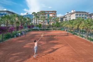 un homme tenant une raquette de tennis sur un court de tennis dans l'établissement Riviera Hotel & Spa, à Alanya