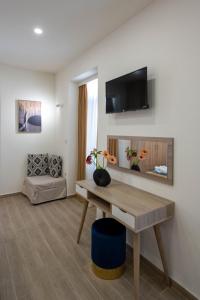 a living room with a table and a tv on a wall at Kalypso Apartments in Kalamata