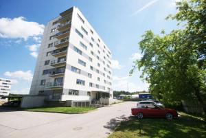 a red car parked in front of a tall building at Gardino Apartment Druskininkai in Druskininkai