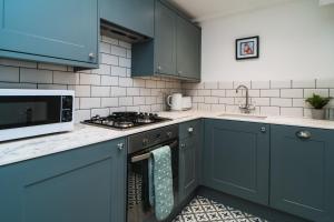 a kitchen with blue cabinets and a stove top oven at Otter's Pocket in Blandford Forum