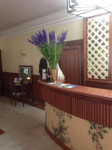 a lobby with a counter with a vase of purple flowers at Hotel Alcione in Marina di Massa