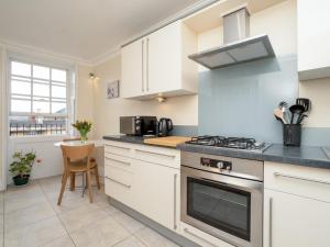 a kitchen with white cabinets and a stove top oven at Pass the Keys Lovely 1 bed flat with parking close to the centre in Bath